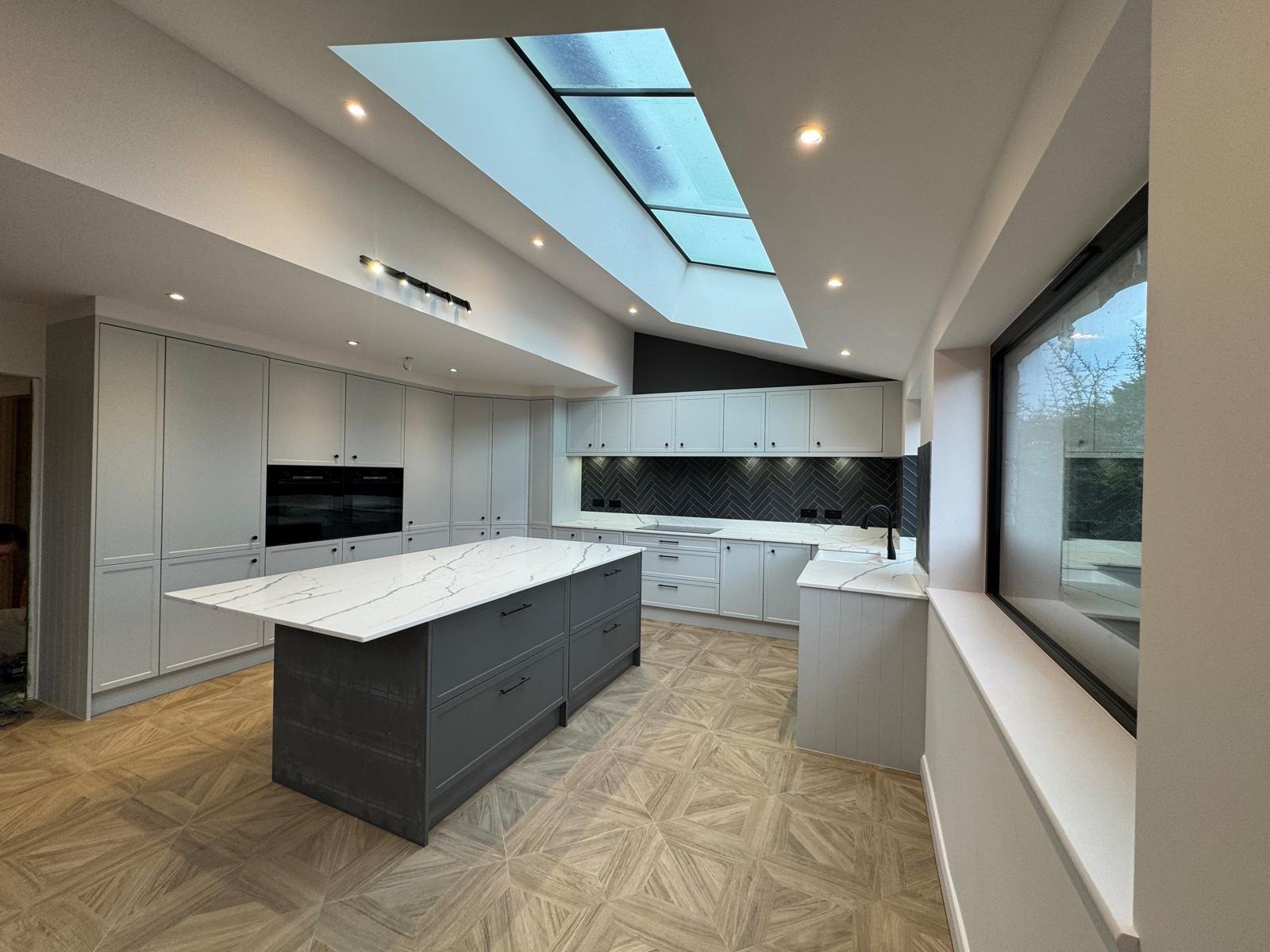 A bright open-plan kitchen extension with an island and bi-fold doors by Professional Polish Builders in Croydon & South London